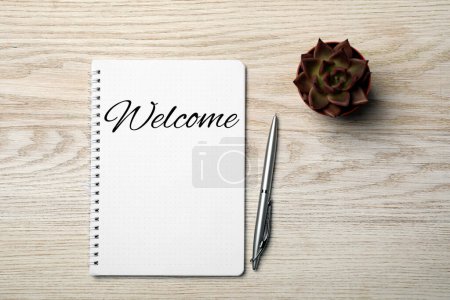 Téléchargez les photos : Carnet de notes avec mot Bienvenue, stylo et plante d'intérieur sur table en bois, pose plate - en image libre de droit