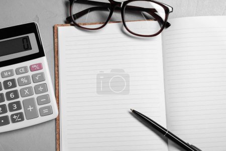 Téléchargez les photos : Word Comptabilité écrite dans le carnet, calculatrice, lunettes et stylo sur la table grise, mise à plat - en image libre de droit