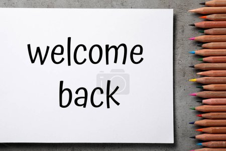 Téléchargez les photos : Papier avec phrase Welcome Back et crayons sur table grise, pose plate - en image libre de droit