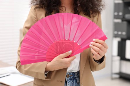 Foto de Mujer con abanico de mano rosa en oficina, primer plano - Imagen libre de derechos
