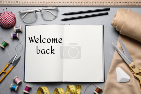 Téléchargez les photos : Carnet avec phrase Welcome Back et accessoires de couture sur fond gris, pose plate - en image libre de droit