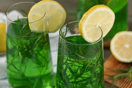 Photo for Glasses of refreshing tarragon drink with lemon slices on table, closeup - Royalty Free Image