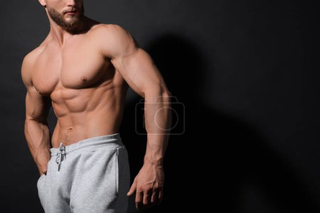 Foto de Hombre musculoso mostrando abdominales sobre fondo negro, primer plano y espacio para el texto. Cuerpo sexy - Imagen libre de derechos