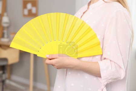 Foto de Mujer con abanico de mano amarillo en casa, primer plano - Imagen libre de derechos