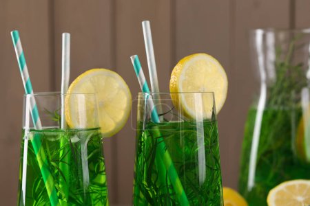 Photo for Glasses of refreshing tarragon drink with lemon slices on wooden background, closeup - Royalty Free Image