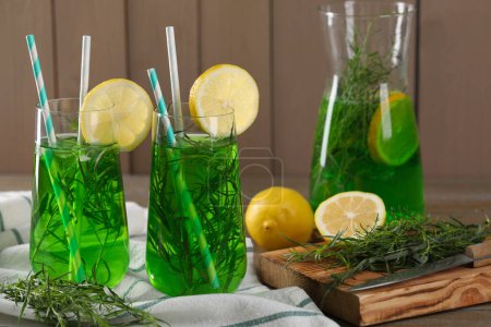 Photo for Jug and glasses of refreshing tarragon drink with lemon slices on table - Royalty Free Image