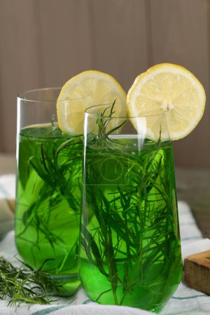 Photo for Glasses of refreshing tarragon drink with lemon slices on table, closeup - Royalty Free Image