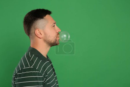 Photo for Handsome man blowing bubble gum on green background, space for text - Royalty Free Image