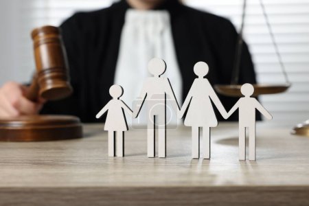 Photo for Family law. Judge with gavel sitting at wooden table, focus on figure of parents and children - Royalty Free Image