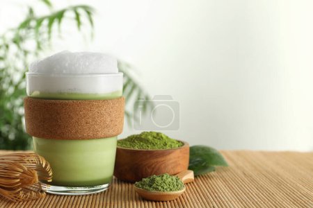 Téléchargez les photos : Coupe en verre de latte matcha frais, poudre et fouet de bambou sur la table. Espace pour le texte - en image libre de droit