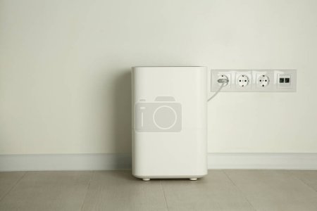 Foto de Moderno humidificador de aire enchufado en toma de corriente en el suelo en interiores - Imagen libre de derechos