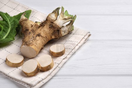 Photo for Cut horseradish root and leaves on white wooden table, closeup. Space for text - Royalty Free Image