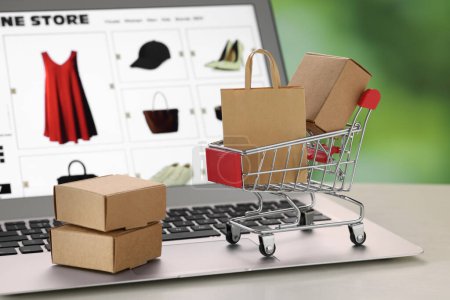 Foto de Mini bolsa de compras, cajas y carro en el ordenador portátil, primer plano. Tienda online - Imagen libre de derechos