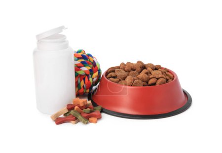 Téléchargez les photos : Aliments secs pour animaux dans un bol, vitamines et jouets isolés sur blanc - en image libre de droit
