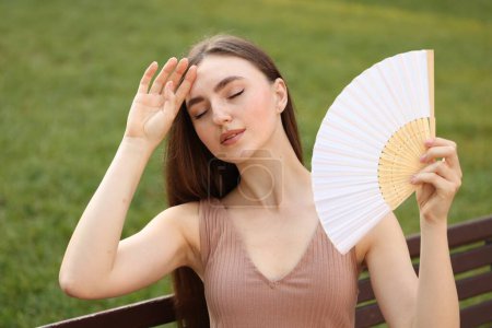 Femme avec ventilateur à main souffrant de chaleur à l'extérieur