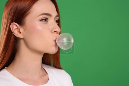 Téléchargez les photos : Belle femme soufflant gomme à bulles sur fond vert, espace pour le texte - en image libre de droit