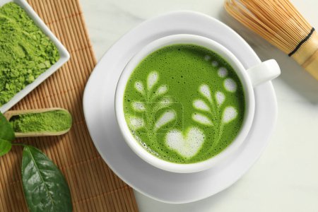 Photo for Delicious matcha latte, powder, leaf and whisk on white table, flat lay - Royalty Free Image