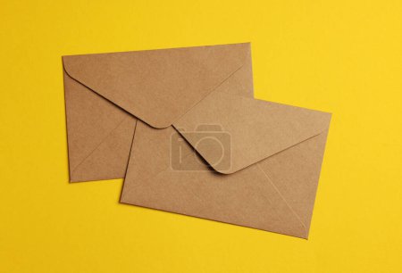 Téléchargez les photos : Enveloppes en papier parchemin sur fond jaune, pose plate - en image libre de droit