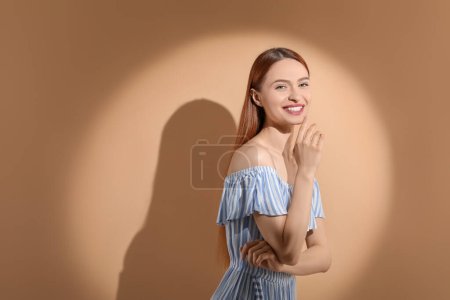Téléchargez les photos : Belle jeune femme au soleil sur fond beige, espace pour le texte - en image libre de droit