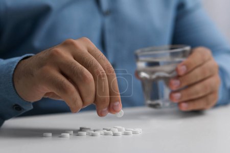 Foto de Hombre con píldoras antidepresivas y vaso de agua en la mesa blanca, primer plano - Imagen libre de derechos