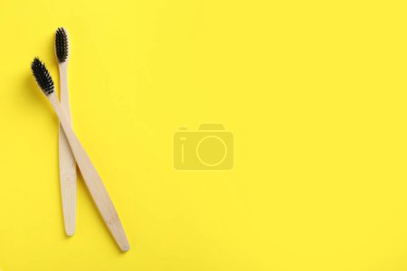 Foto de Dos cepillos de dientes de bambú sobre fondo amarillo, plano. Espacio para texto - Imagen libre de derechos