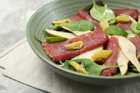 Photo for Delicious bresaola salad in bowl on light textured table, closeup - Royalty Free Image