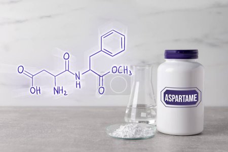 Téléchargez les photos : Formule chimique structurelle de l'aspartame. Édulcorant artificiel en boîte de Pétri et bouteille sur table grise - en image libre de droit