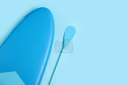 Photo for Board and paddle for standup paddleboarding (SUP) on light blue background, flat lay. Space for text - Royalty Free Image