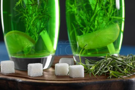Photo for Glasses of homemade refreshing tarragon drink, sprigs and sugar cubes on wooden board, closeup - Royalty Free Image