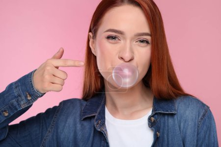 Téléchargez les photos : Portrait de belle femme soufflant gomme à bulles sur fond rose - en image libre de droit