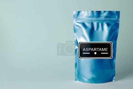 Foto de Aspartamo. Paquete de lámina azul con edulcorante artificial sobre fondo claro, espacio para texto - Imagen libre de derechos
