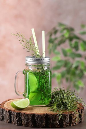 Photo for Mason jar of homemade refreshing tarragon drink with lemon slices and sprigs on wooden stump - Royalty Free Image