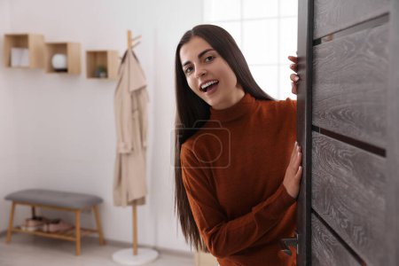 Téléchargez les photos : Femme heureuse debout près de la porte, espace pour le texte. Invitation à venir à l'intérieur - en image libre de droit