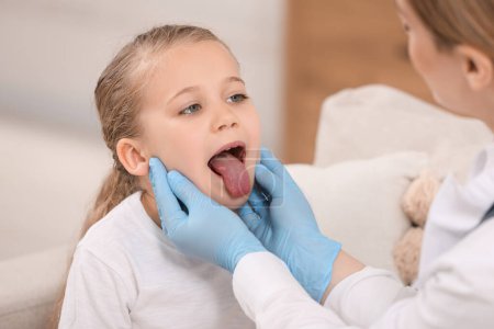Foto de Médico en guantes examinando la cavidad oral de la niña en interiores - Imagen libre de derechos