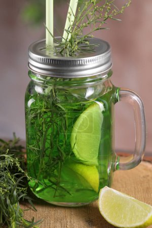 Photo for Mason jar of homemade refreshing tarragon drink with lemon slices and sprigs on wooden stump, closeup - Royalty Free Image