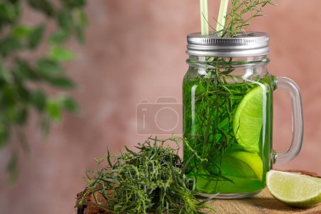 Photo for Mason jar of homemade refreshing tarragon drink with lemon slices and sprigs on wooden stump, closeup. Space for text - Royalty Free Image