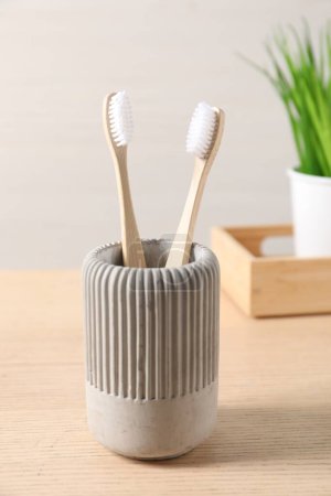 Téléchargez les photos : Brosses à dents en bambou dans le support sur une table en bois - en image libre de droit