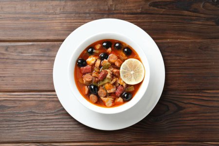 Téléchargez les photos : Soupe de viande solyanka aux saucisses, olives et légumes sur table en bois, vue sur le dessus - en image libre de droit