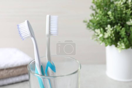 Téléchargez les photos : Brosses à dents en plastique dans un support en verre sur fond clair, gros plan - en image libre de droit