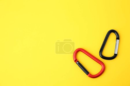 Photo for Two metal carabiners on yellow background, flat lay. Space for text - Royalty Free Image