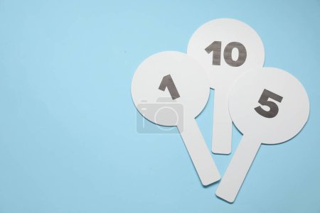 Photo for Auction paddles with numbers on light blue background, top view. Space for text - Royalty Free Image