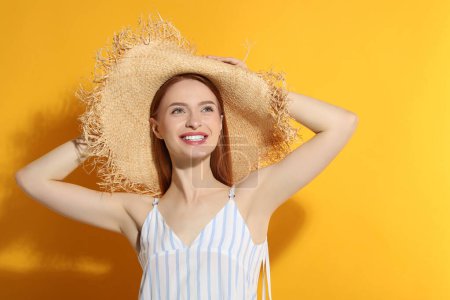 Photo for Beautiful young woman in straw hat on orange background, space for text - Royalty Free Image