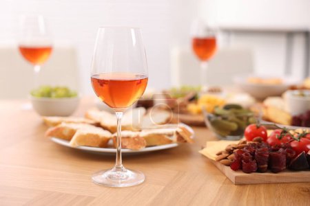 Photo for Rose wine and assorted appetizers served on wooden table indoors, selective focus. Space for text - Royalty Free Image