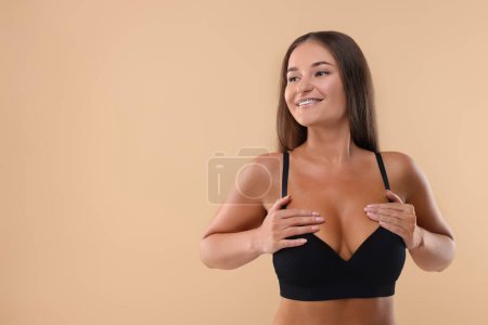 Téléchargez les photos : Portrait de jeune femme avec un beau sein sur fond beige. Espace pour le texte - en image libre de droit