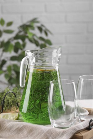 Photo for Jug of homemade refreshing tarragon drink and glasses on table - Royalty Free Image