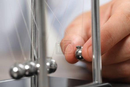 Photo for Man playing with Newton's cradle, closeup. Physics law of energy conservation - Royalty Free Image