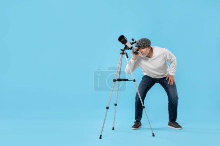 Senior astronomer looking at stars through telescope on light blue background Space for text