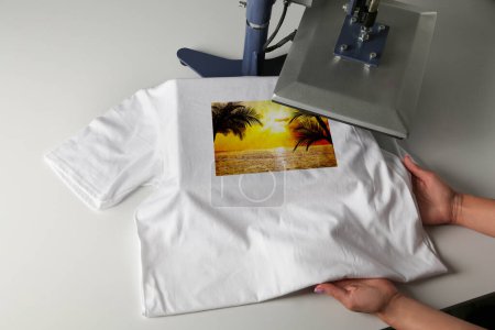 Photo for Custom t-shirt. Woman using heat press to print beautiful image of tropical seascape - Royalty Free Image