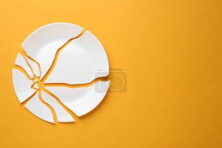 Photo for Pieces of broken ceramic plate on orange background, flat lay. Space for text - Royalty Free Image