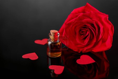 Photo for Bottle of love potion, paper hearts and red rose on mirror surface - Royalty Free Image